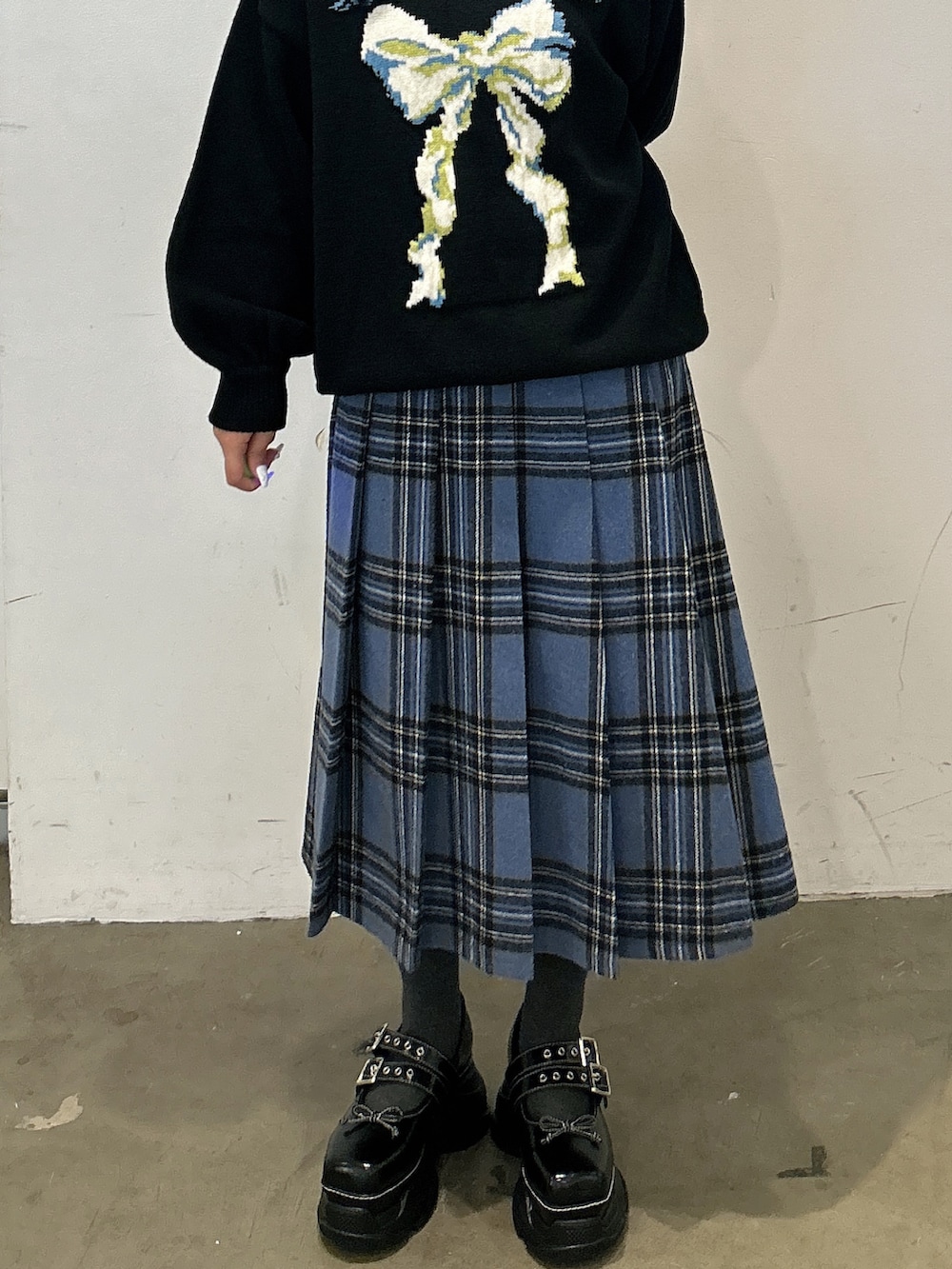 ブラック系のニット/セーター、ブルー系のスカート、ブラック系のスニーカーを着用したレディースの秋コーディネートの5枚目の写真