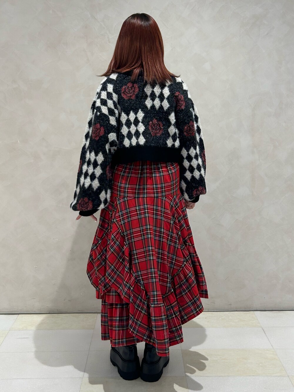 レッド系のスカート、ブラック系のドレスシューズ、ブラック系のカーディガン/ボレロを着用したレディースの秋コーディネートの3枚目の写真