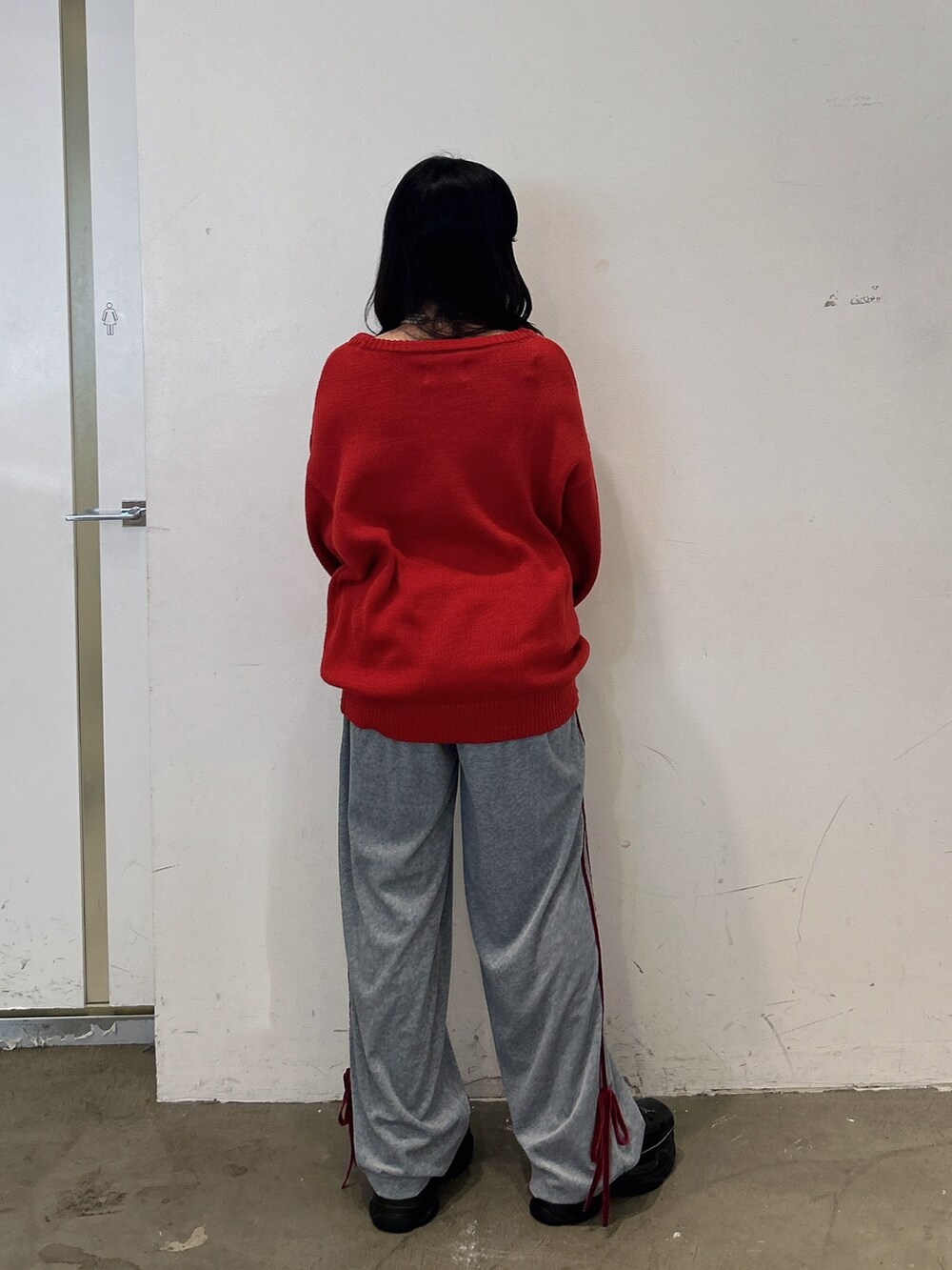 レッド系のニット/セーター、グレー系のその他パンツ、ブラック系のスニーカーを着用したレディースの秋コーディネートの3枚目の写真