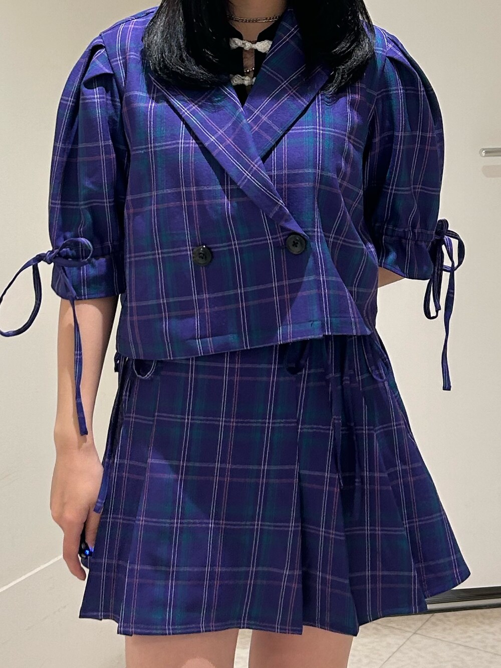 パープル系のテーラードジャケット、パープル系のスカート、ブラック系のブーツを着用したレディースの冬コーディネートの4枚目の写真