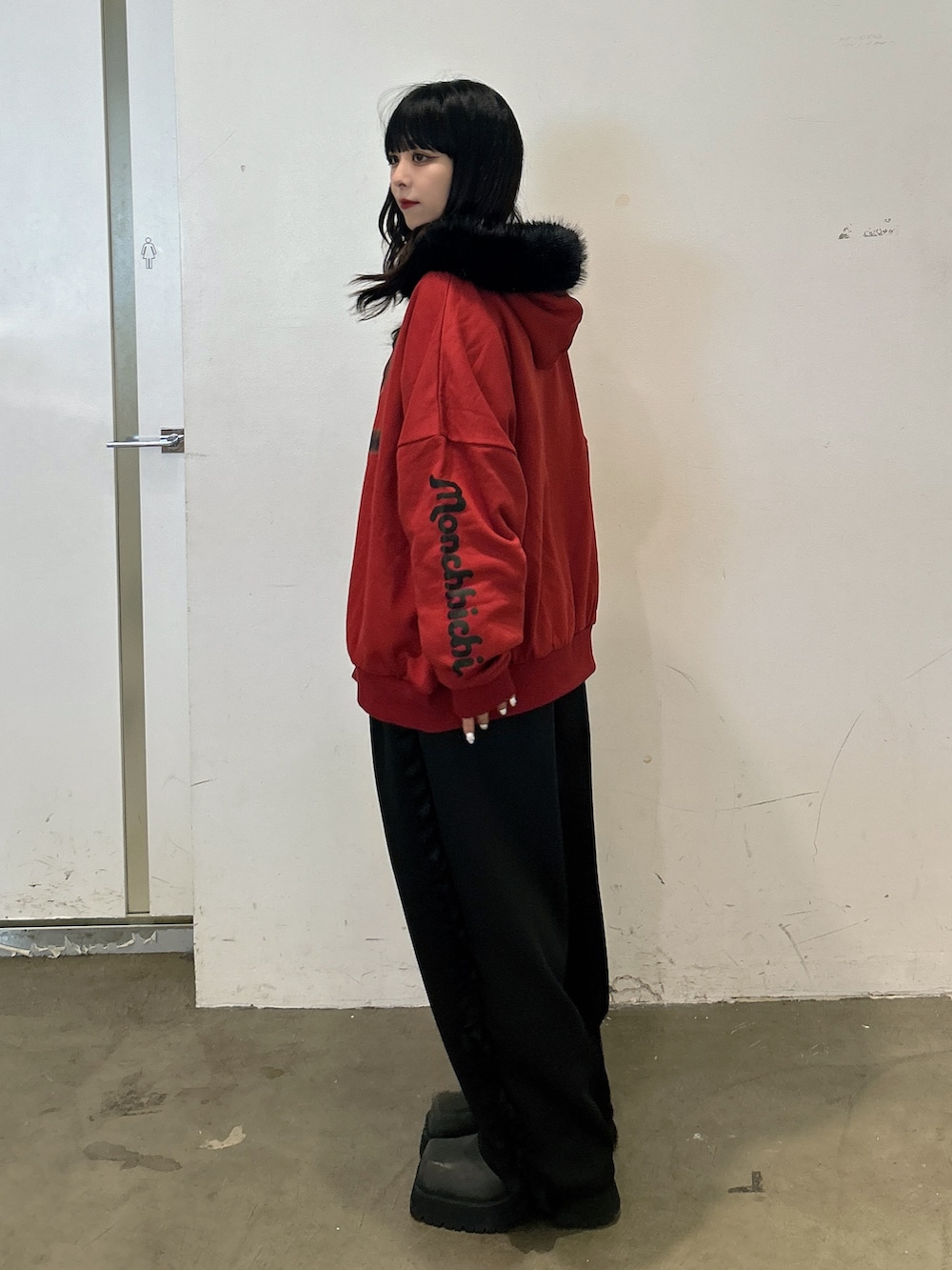 レッド系のパーカー、ブラック系のその他パンツ、ブラック系のブーツを着用したレディースの秋コーディネートの2枚目の写真