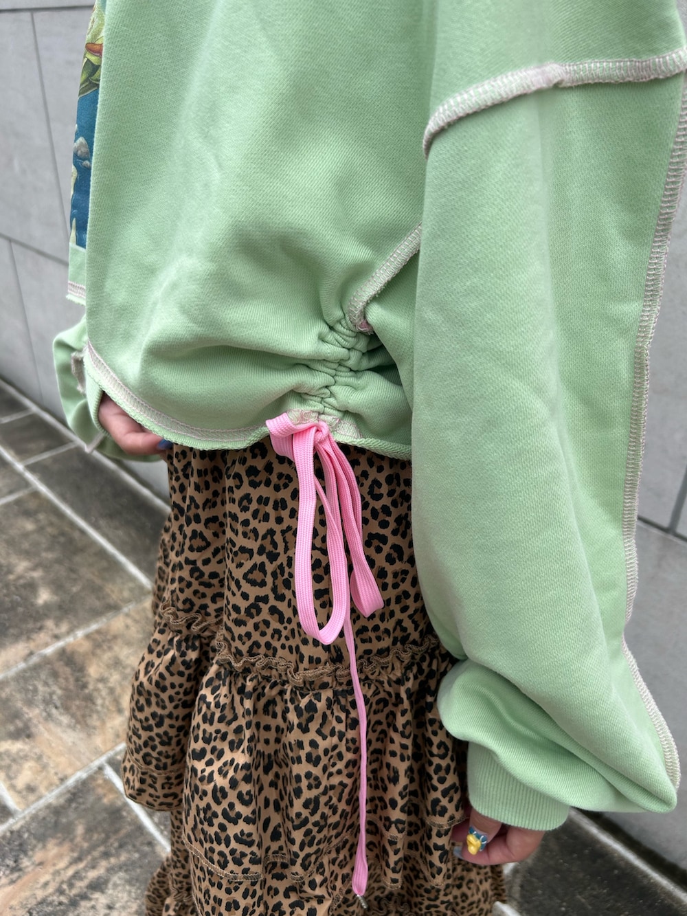 ブラウン系のスカート、グリーン系のスウェット、ブラック系のブーツを着用したレディースの夏コーディネートの6枚目の写真