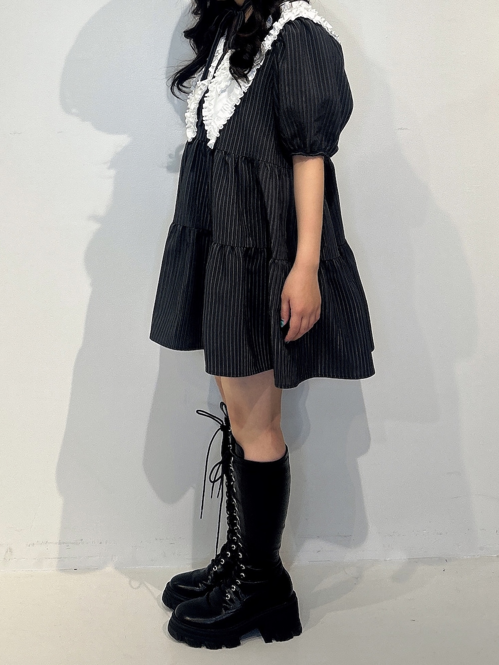 グレー系のワンピース、ブラック系のブーツを着用したレディースの冬コーディネートの2枚目の写真