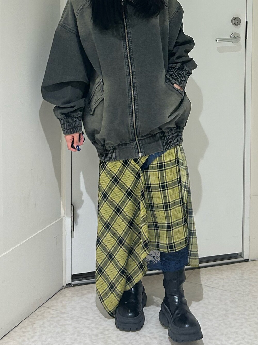 ブラック系のデニムジャケット、イエロー系のスカート、ブラック系のブーツを着用したレディースの春コーディネートの4枚目の写真