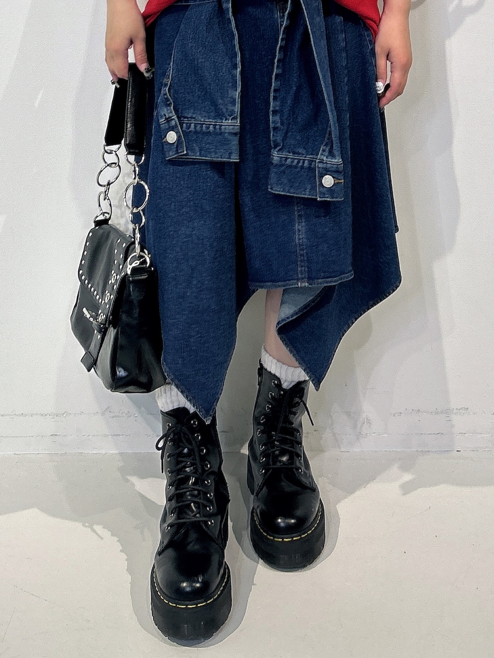 レッド系のTシャツ/カットソー、ブルー系のスカート、ブラック系のブーツを着用したレディースの春コーディネートの5枚目の写真