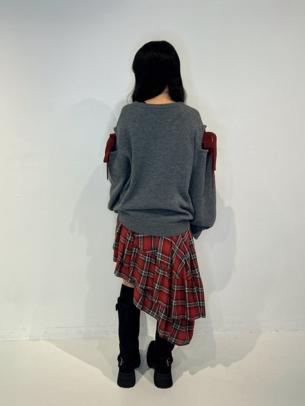 ブラック系のブーツ、レッド系のスカート、グレー系のニット/セーターを着用したレディースの秋コーディネートの3枚目の写真
