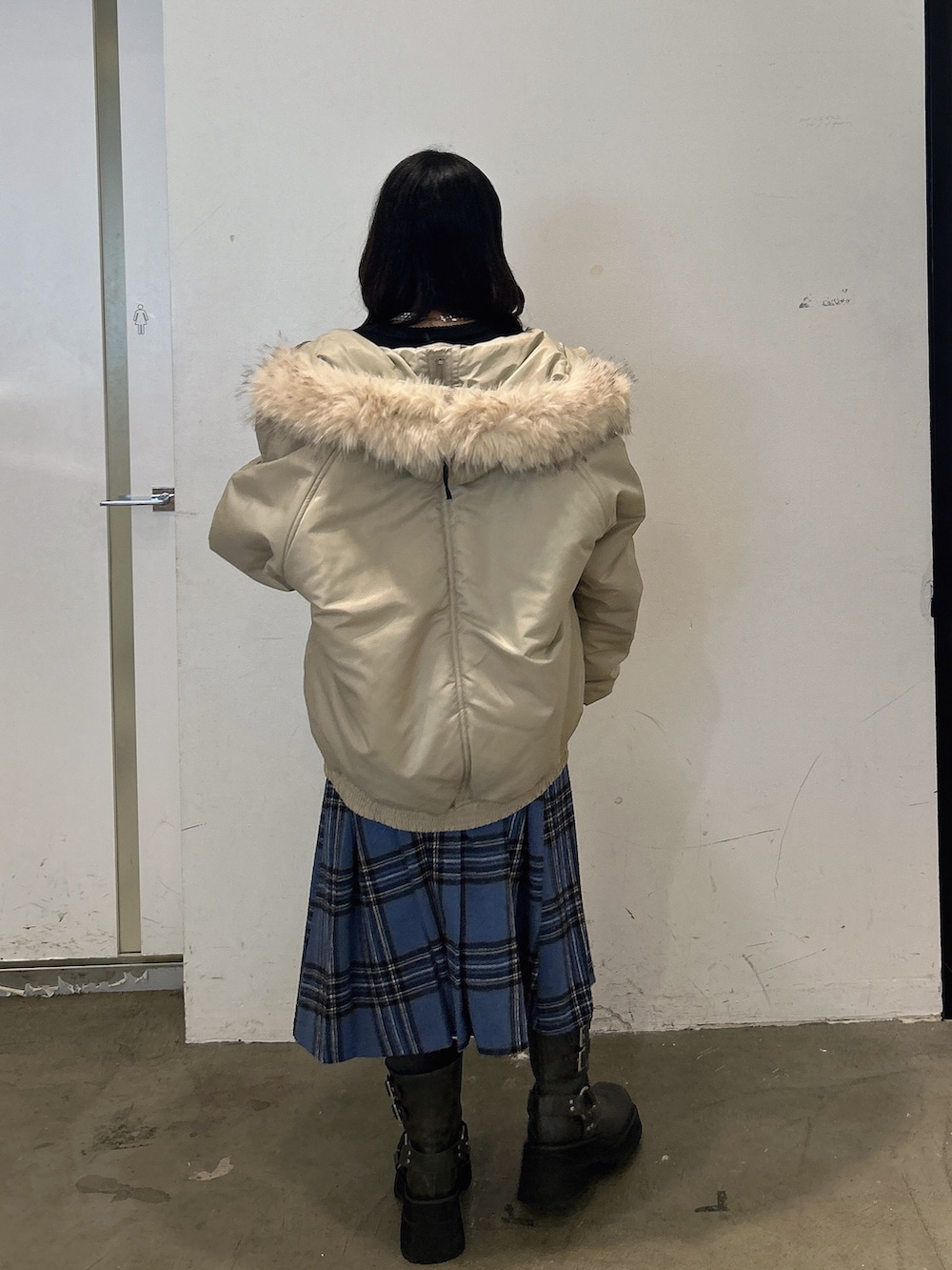 ブラック系のニット/セーター、ブルー系のスカート、ブラック系のブーツを着用したレディースの秋コーディネートの3枚目の写真