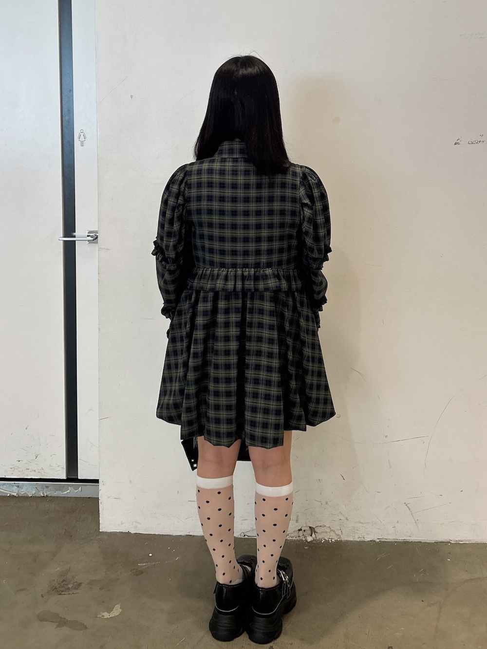 グリーン系のワンピース、ブラック系のショルダーバッグ、ブラック系のスニーカーを着用したレディースの秋コーディネートの3枚目の写真