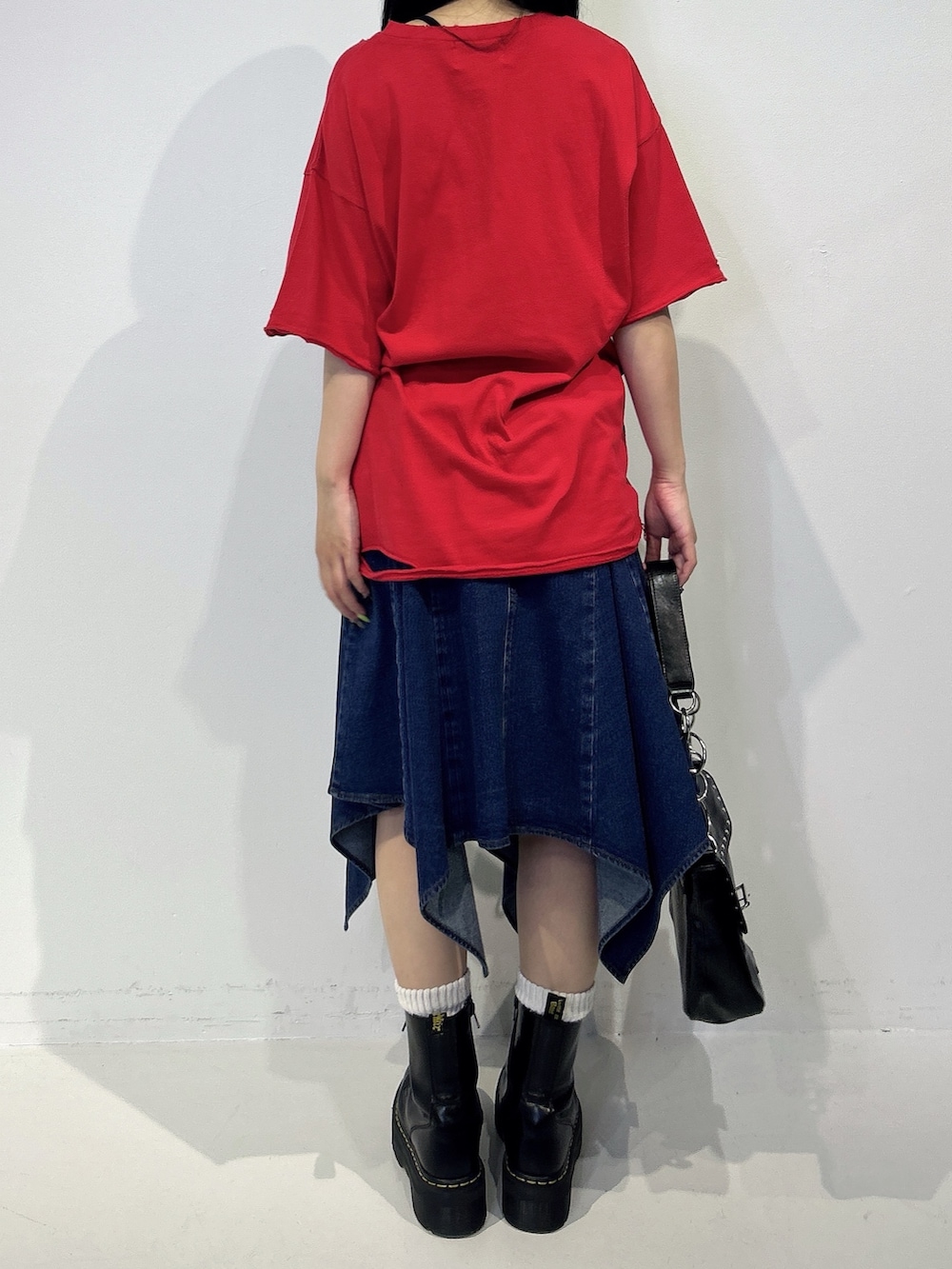 レッド系のTシャツ/カットソー、ブルー系のスカート、ブラック系のブーツを着用したレディースの春コーディネートの3枚目の写真