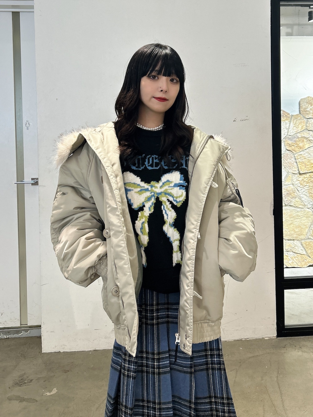 ブラック系のニット/セーター、ブルー系のスカート、ブラック系のブーツを着用したレディースの秋コーディネートの5枚目の写真