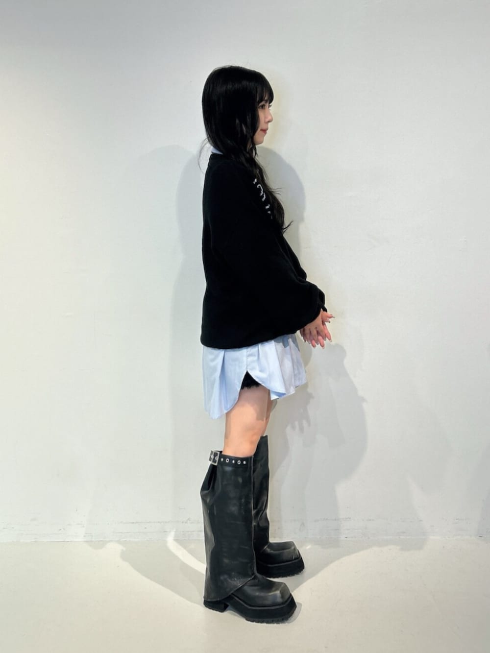 ブラック系のブーツ、ブラック系のニット/セーター、ブルー系のシャツ/ブラウスを着用したレディースの夏コーディネートの2枚目の写真