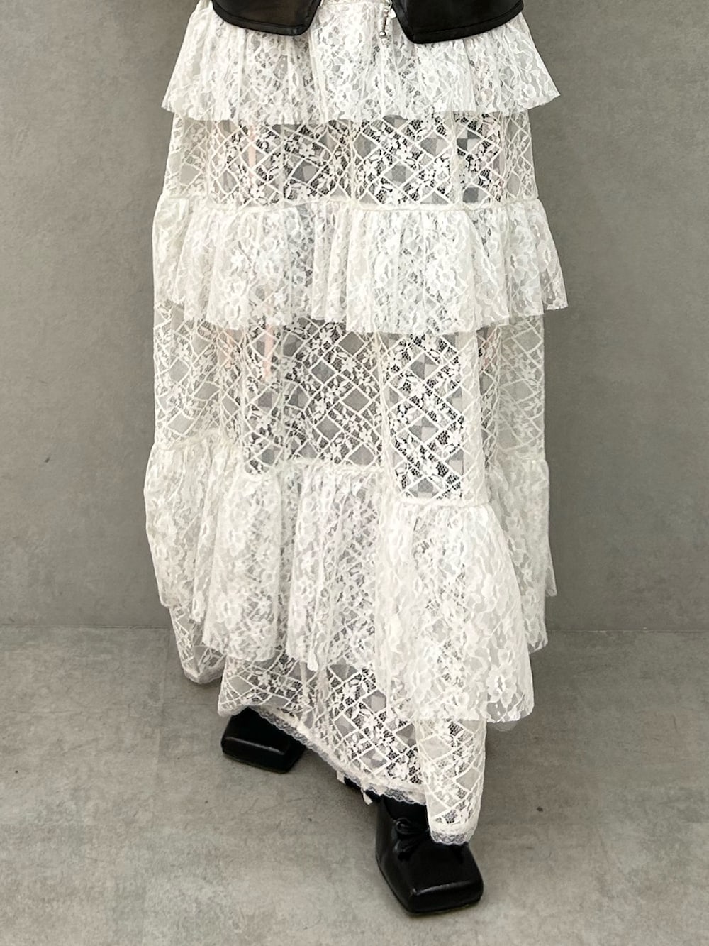 ブラック系のパンプス、ホワイト系のワンピース、ブラック系のベストを着用したレディースの冬コーディネートの6枚目の写真