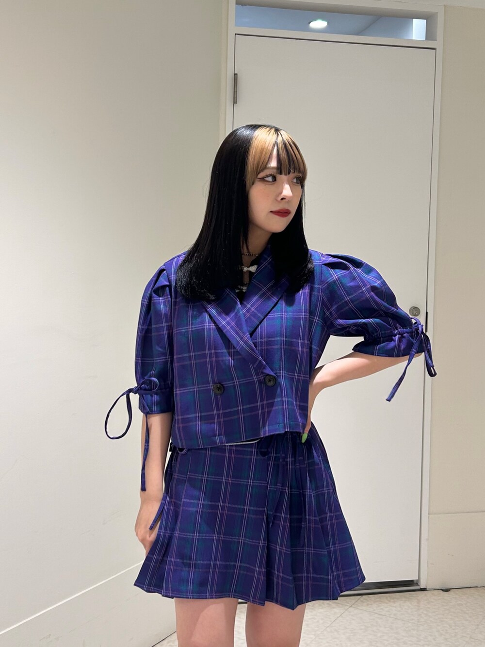 パープル系のテーラードジャケット、パープル系のスカート、ブラック系のブーツを着用したレディースの冬コーディネートの7枚目の写真