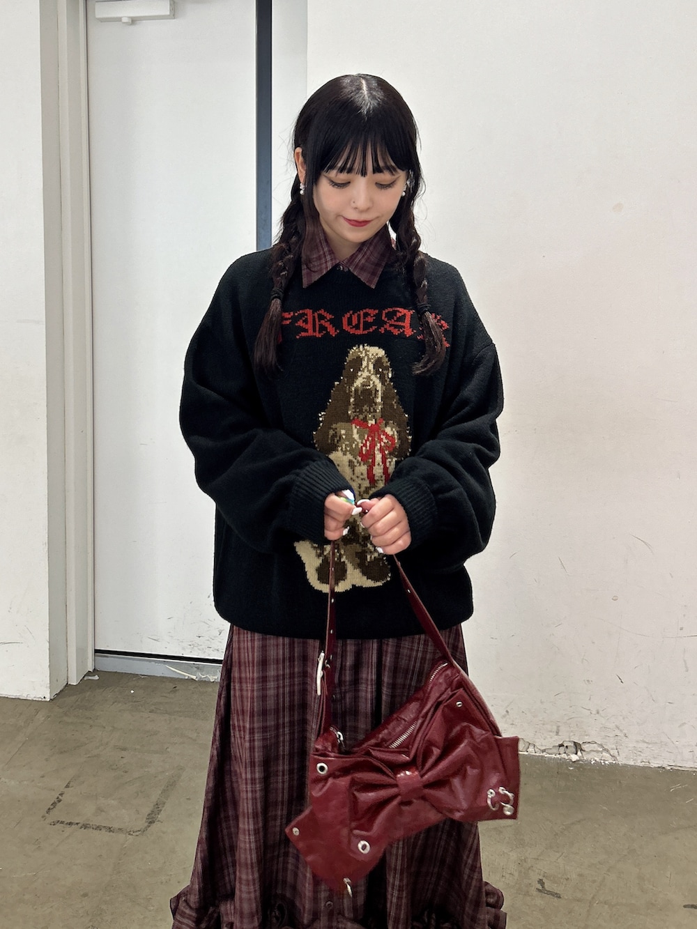 ブラック系のニット/セーター、レッド系のワンピース、レッド系のショルダーバッグを着用したレディースの秋コーディネートの4枚目の写真