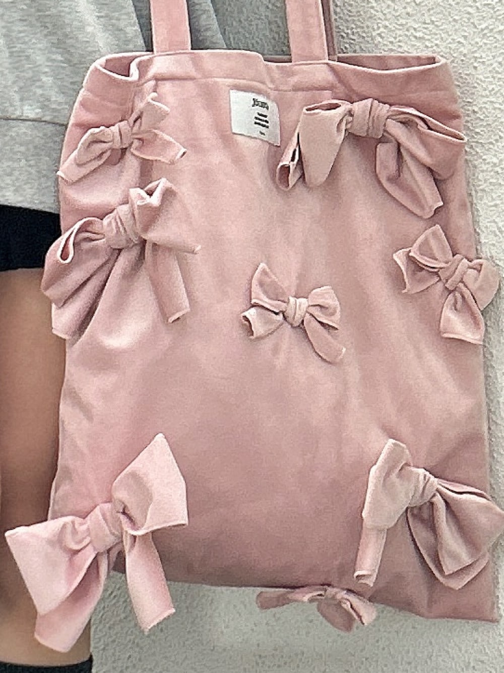 グレー系のパーカー、ピンク系のトートバッグ、ブラック系のブーツを着用したレディースの秋コーディネートの5枚目の写真