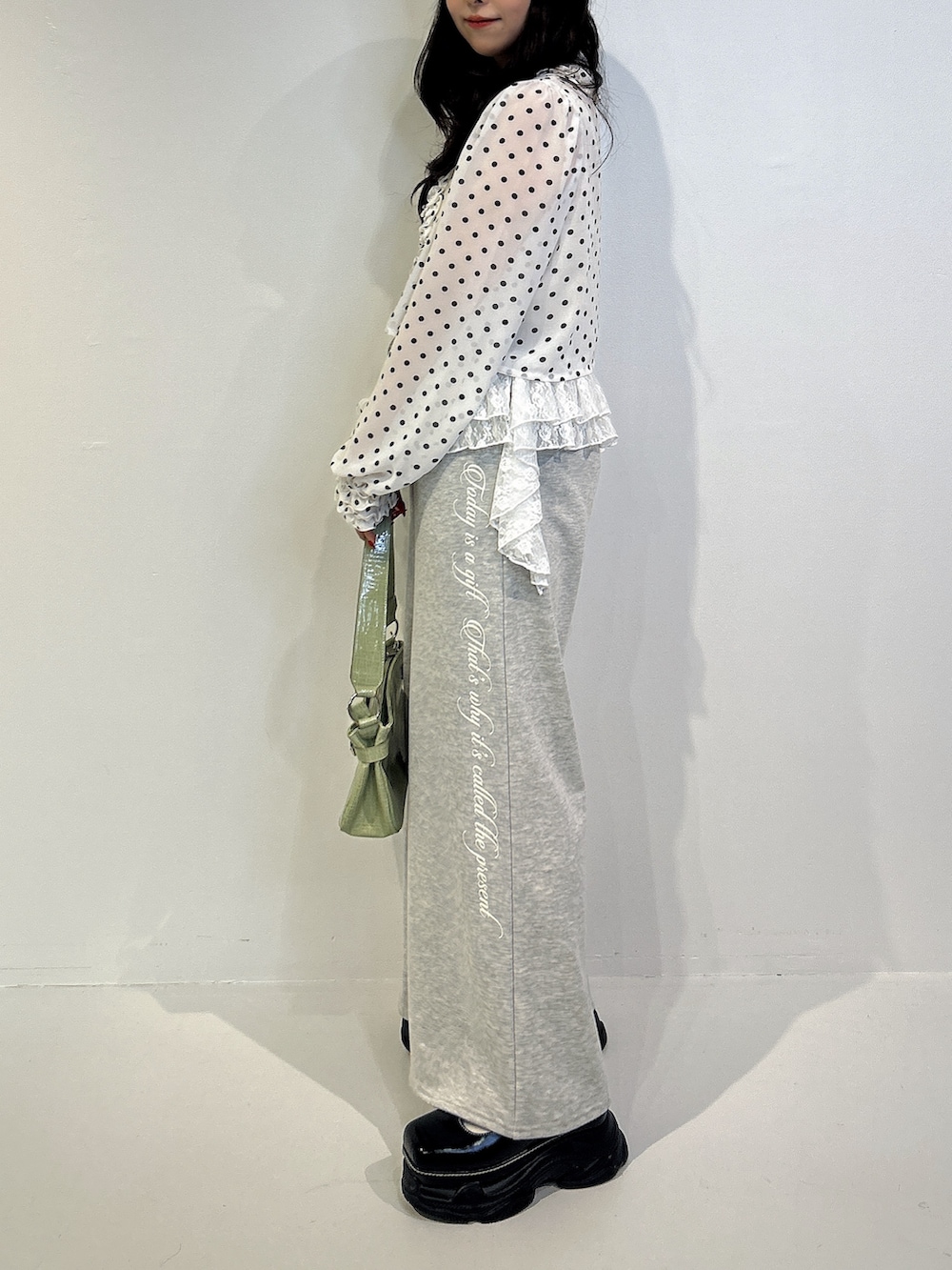 グレー系のスウェットパンツ、ブラック系のローファー、グリーン系のハンドバッグを着用したレディースの秋コーディネートの2枚目の写真