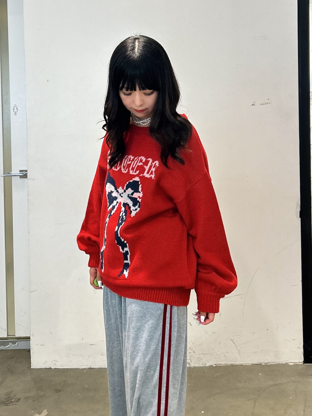 レッド系のニット/セーター、グレー系のその他パンツ、ブラック系のスニーカーを着用したレディースの秋コーディネートの4枚目の写真