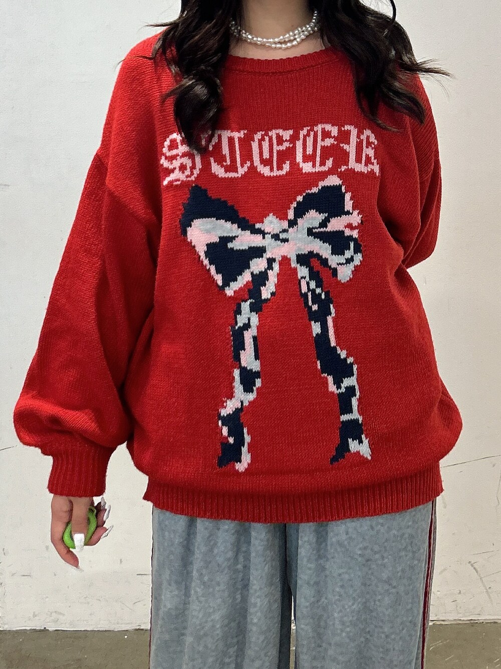 レッド系のニット/セーター、グレー系のその他パンツ、ブラック系のスニーカーを着用したレディースの秋コーディネートの5枚目の写真