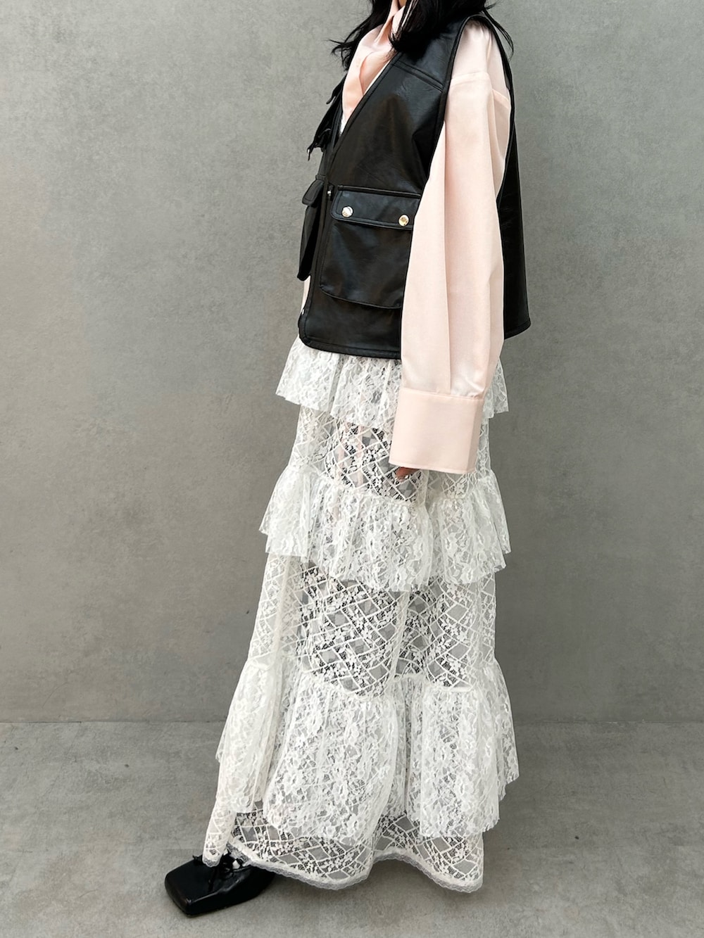 ブラック系のパンプス、ホワイト系のワンピース、ブラック系のベストを着用したレディースの冬コーディネートの2枚目の写真