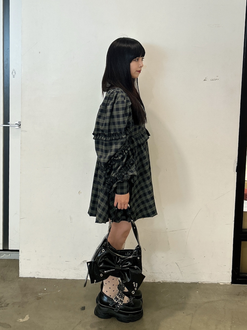 グリーン系のワンピース、ブラック系のショルダーバッグ、ブラック系のスニーカーを着用したレディースの秋コーディネートの2枚目の写真