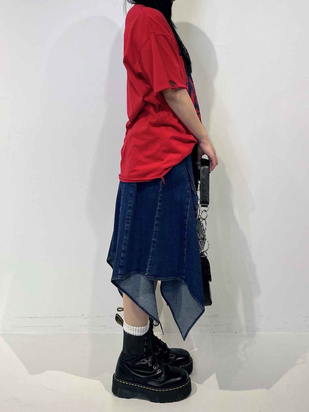 レッド系のTシャツ/カットソー、ブルー系のスカート、ブラック系のブーツを着用したレディースの春コーディネートの2枚目の写真