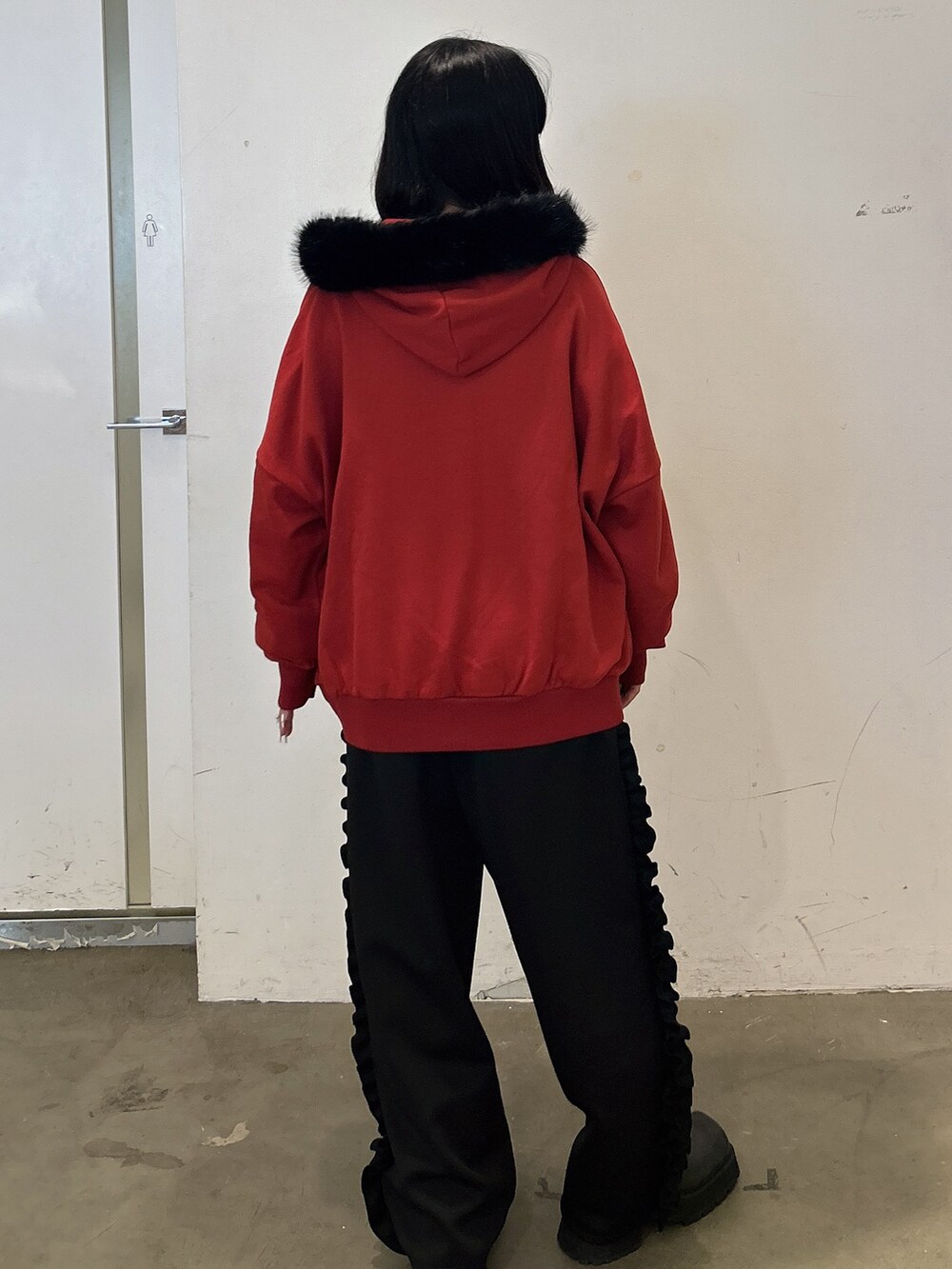 レッド系のパーカー、ブラック系のその他パンツ、ブラック系のブーツを着用したレディースの秋コーディネートの3枚目の写真