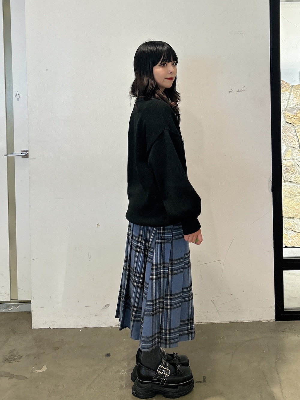 ブラック系のニット/セーター、ブルー系のスカート、ブラック系のスニーカーを着用したレディースの秋コーディネートの2枚目の写真