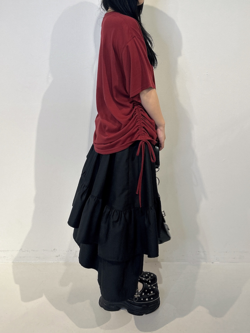 レッド系のTシャツ/カットソー、ブラック系のスカート、ブラック系のハンドバッグを着用したレディースの春コーディネートの2枚目の写真