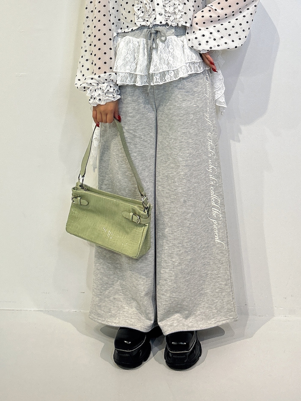 グレー系のスウェットパンツ、ブラック系のローファー、グリーン系のハンドバッグを着用したレディースの秋コーディネートの5枚目の写真