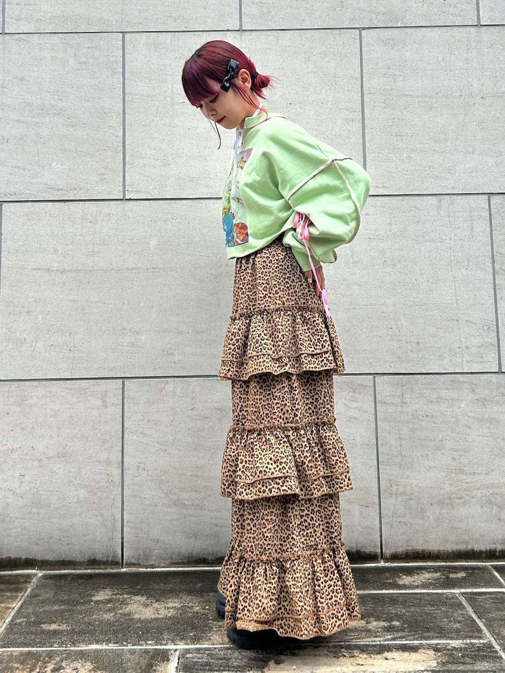 ブラウン系のスカート、グリーン系のスウェット、ブラック系のブーツを着用したレディースの夏コーディネートの2枚目の写真