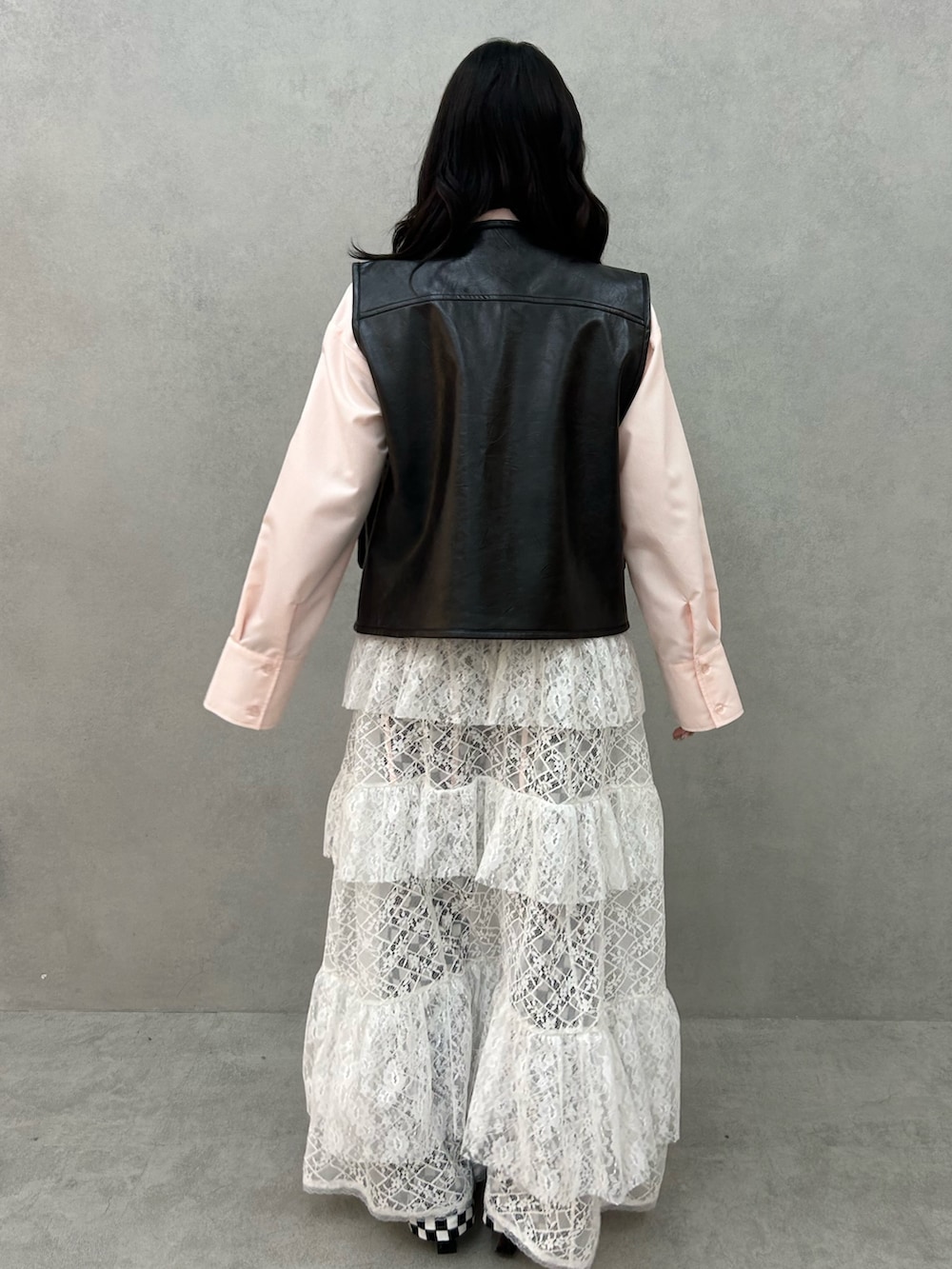 ブラック系のパンプス、ホワイト系のワンピース、ブラック系のベストを着用したレディースの冬コーディネートの3枚目の写真