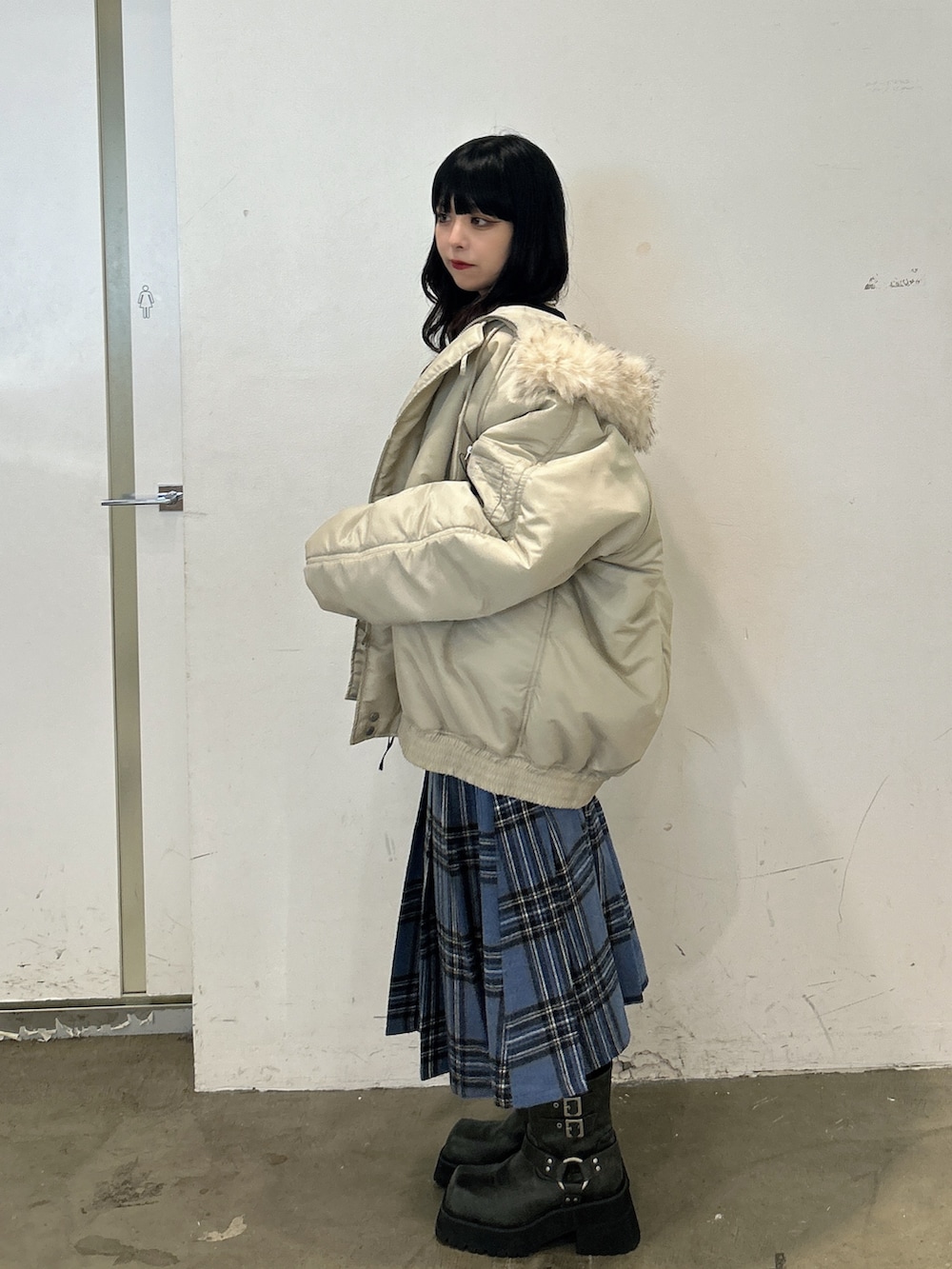 ブラック系のニット/セーター、ブルー系のスカート、ブラック系のブーツを着用したレディースの秋コーディネートの2枚目の写真