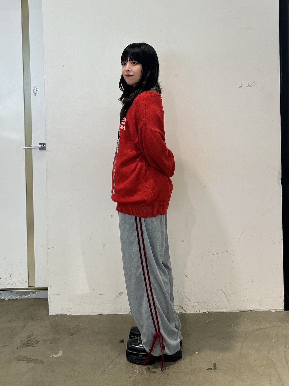 レッド系のニット/セーター、グレー系のその他パンツ、ブラック系のスニーカーを着用したレディースの秋コーディネートの2枚目の写真