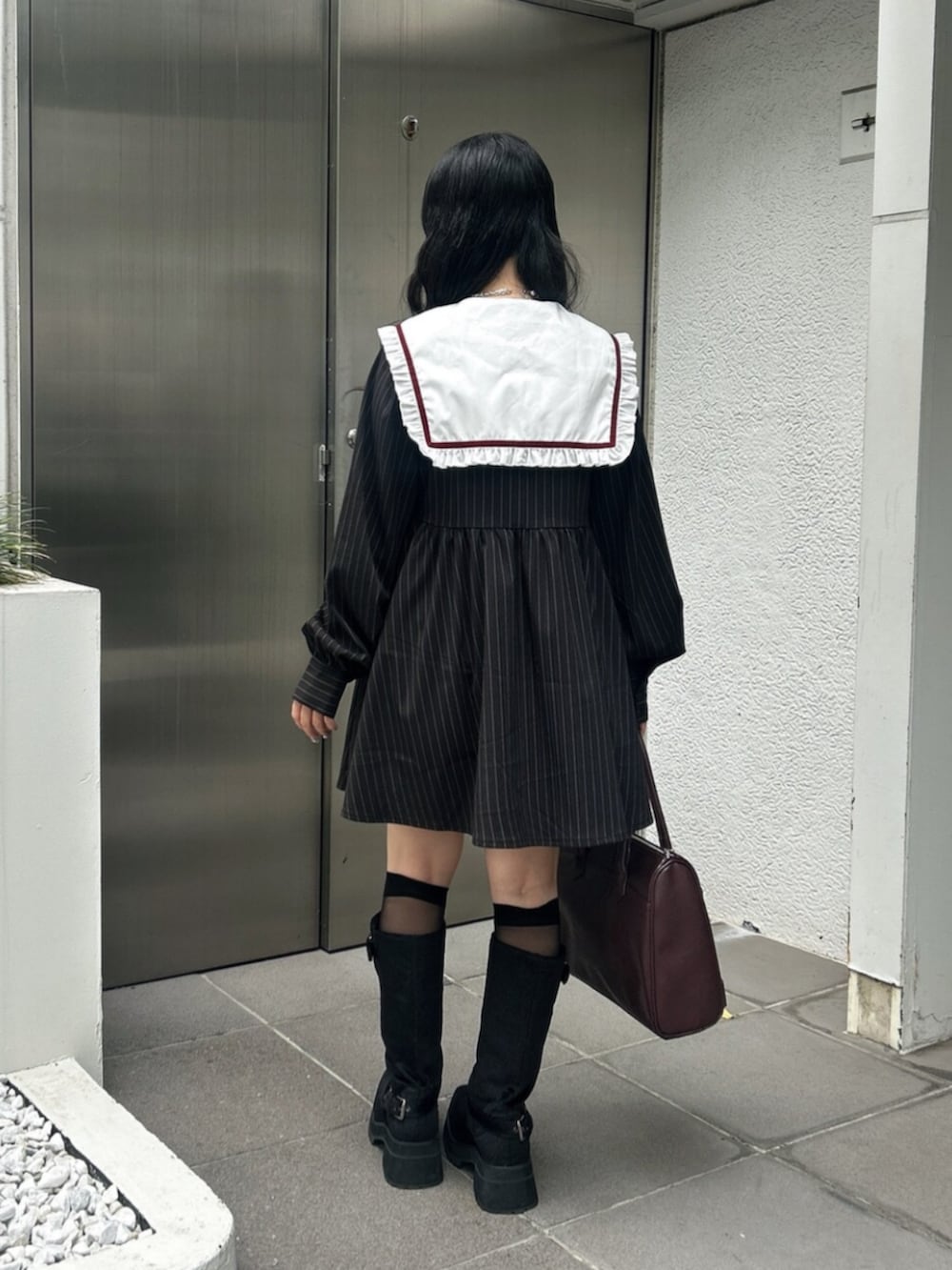 ブラック系のブーツ、ブラック系のワンピース、レッド系のハンドバッグを着用したレディースの秋コーディネートの3枚目の写真