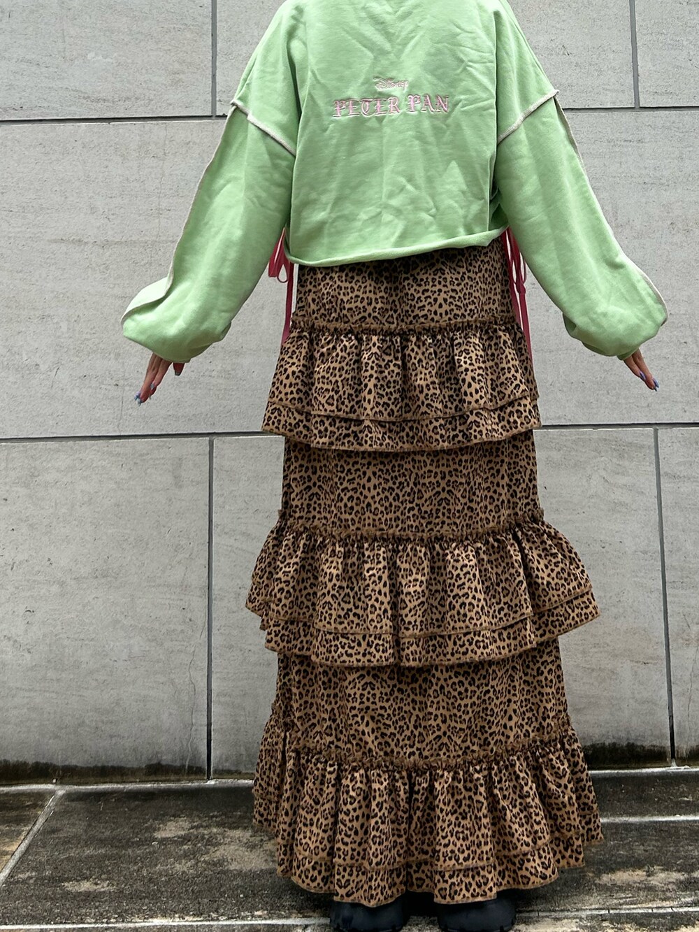 ブラウン系のスカート、グリーン系のスウェット、ブラック系のブーツを着用したレディースの夏コーディネートの3枚目の写真