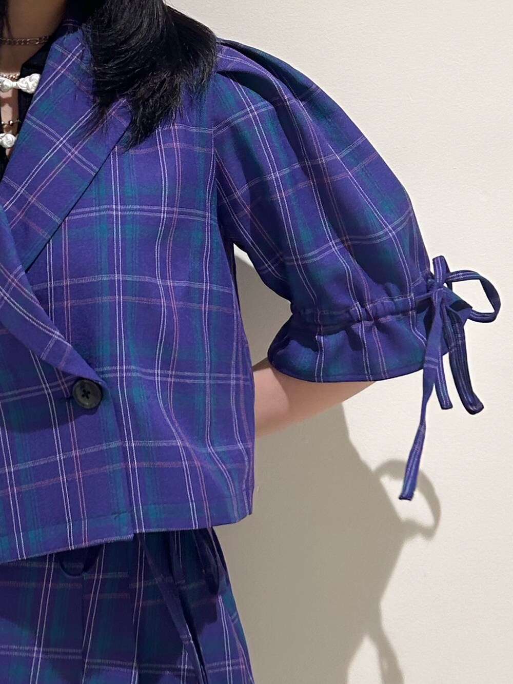 パープル系のテーラードジャケット、パープル系のスカート、ブラック系のブーツを着用したレディースの冬コーディネートの5枚目の写真