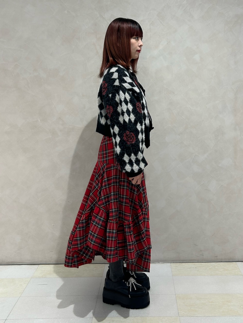 レッド系のスカート、ブラック系のドレスシューズ、ブラック系のカーディガン/ボレロを着用したレディースの秋コーディネートの2枚目の写真