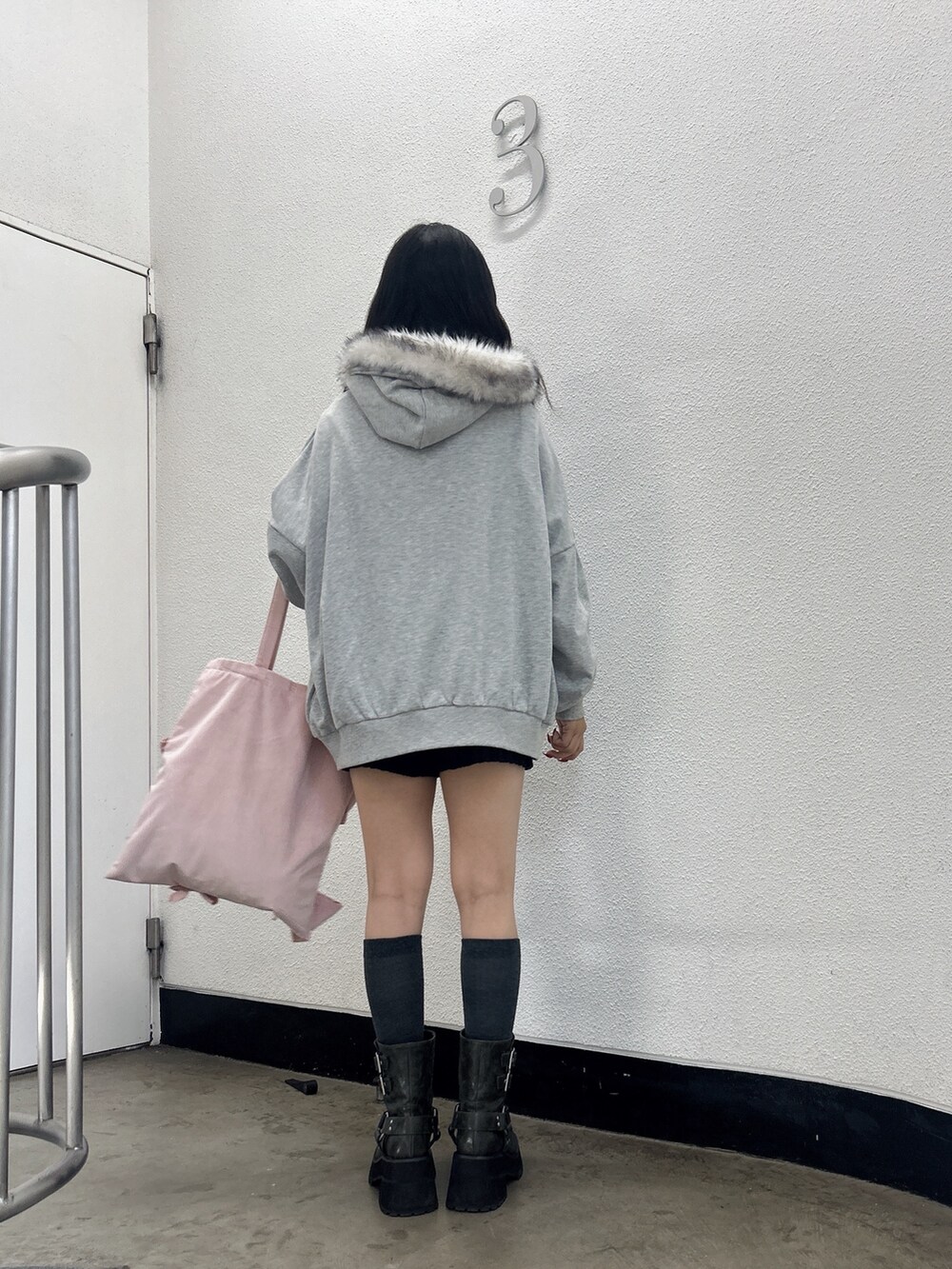 グレー系のパーカー、ピンク系のトートバッグ、ブラック系のブーツを着用したレディースの秋コーディネートの3枚目の写真