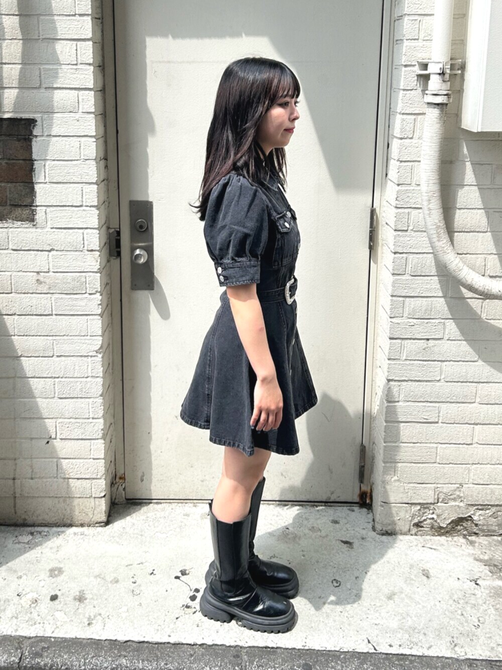 ブラック系のブーツ、ブラック系のワンピース、ホワイト系のチョーカーを着用したレディースの春コーディネートの2枚目の写真