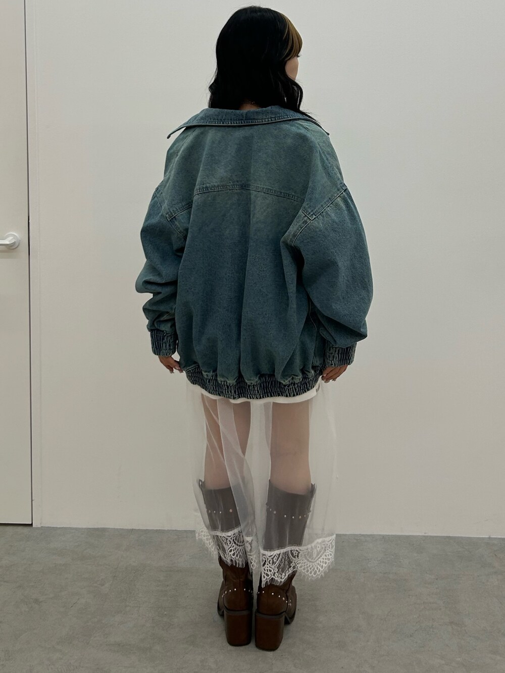 ブルー系のデニムジャケット、ホワイト系のワンピース、ブラウン系のブーツを着用したレディースの冬コーディネートの3枚目の写真