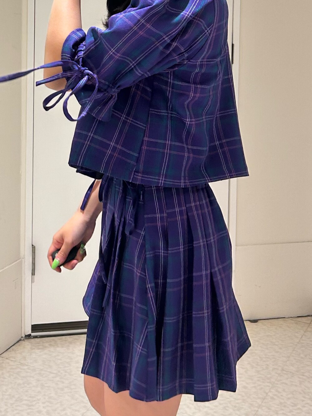 パープル系のテーラードジャケット、パープル系のスカート、ブラック系のブーツを着用したレディースの冬コーディネートの6枚目の写真