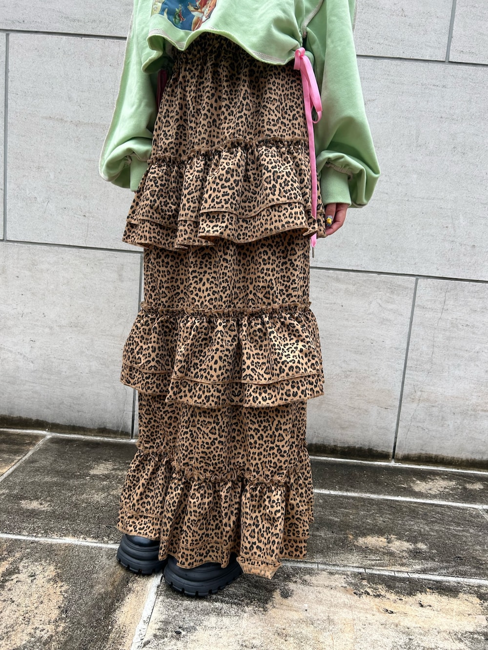 ブラウン系のスカート、グリーン系のスウェット、ブラック系のブーツを着用したレディースの夏コーディネートの7枚目の写真