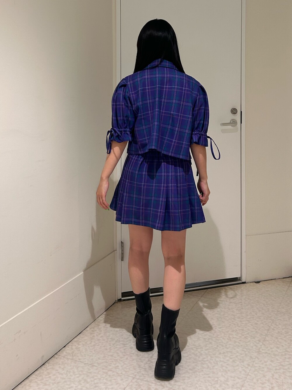 パープル系のテーラードジャケット、パープル系のスカート、ブラック系のブーツを着用したレディースの冬コーディネートの3枚目の写真