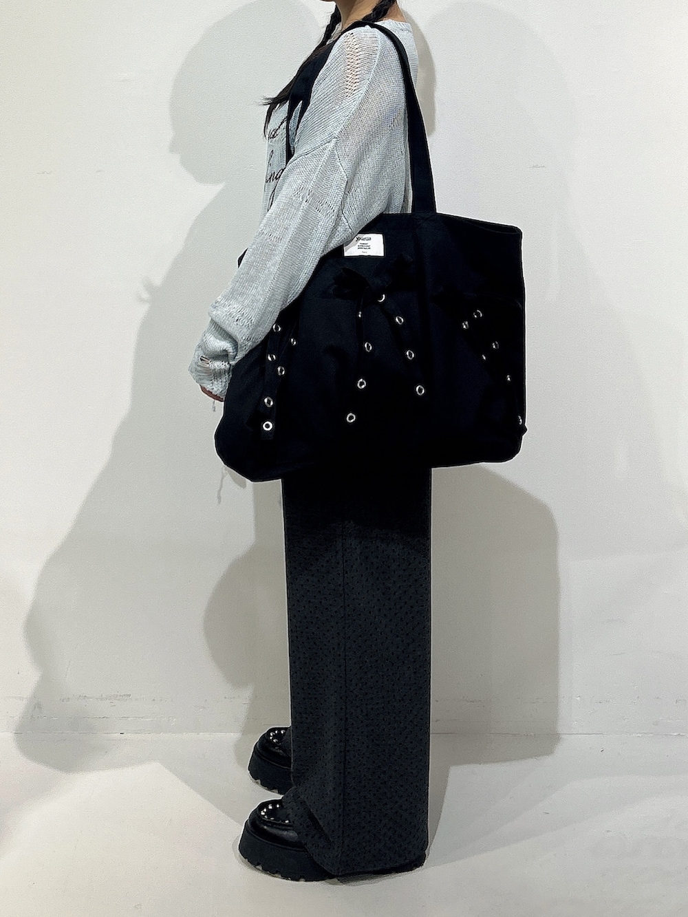 ブラック系のトートバッグ、ブルー系のニット/セーター、グレー系のスウェットパンツを着用したレディースの冬コーディネートの2枚目の写真