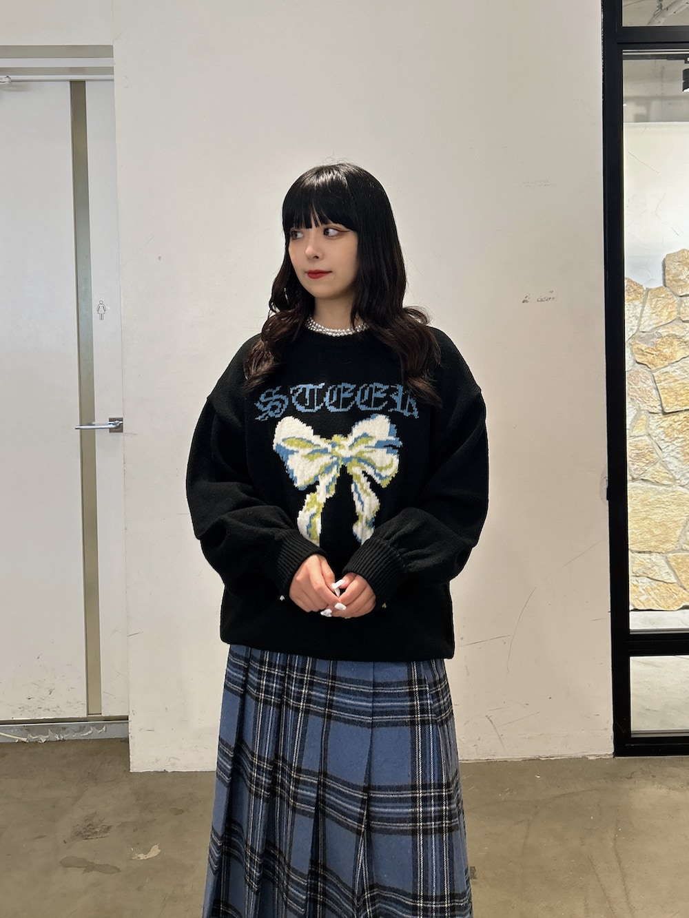 ブラック系のニット/セーター、ブルー系のスカート、ブラック系のスニーカーを着用したレディースの秋コーディネートの4枚目の写真