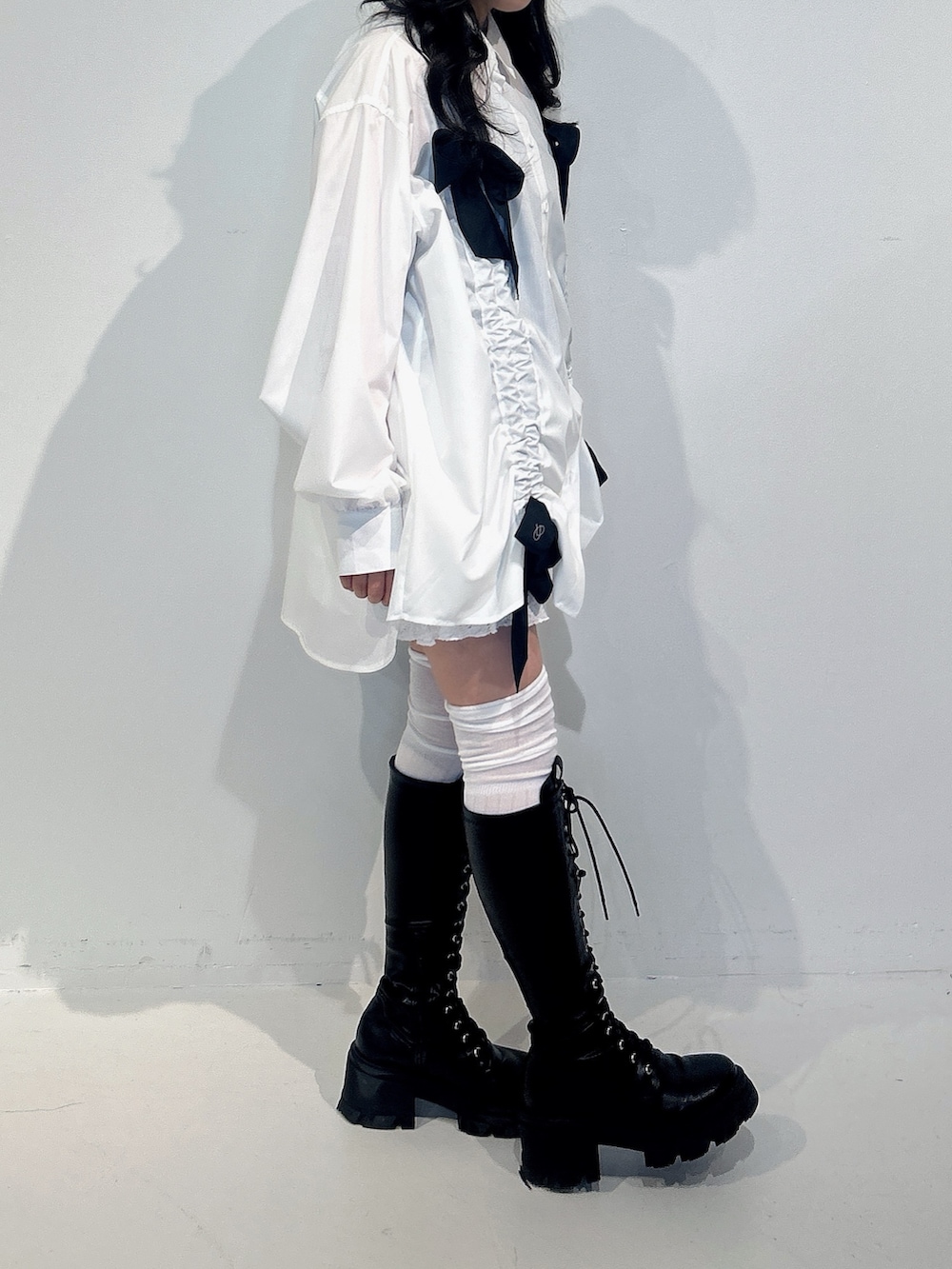 ホワイト系のシャツ/ブラウス、ホワイト系のスカート、ブラック系のブーツを着用したレディースの冬コーディネートの2枚目の写真