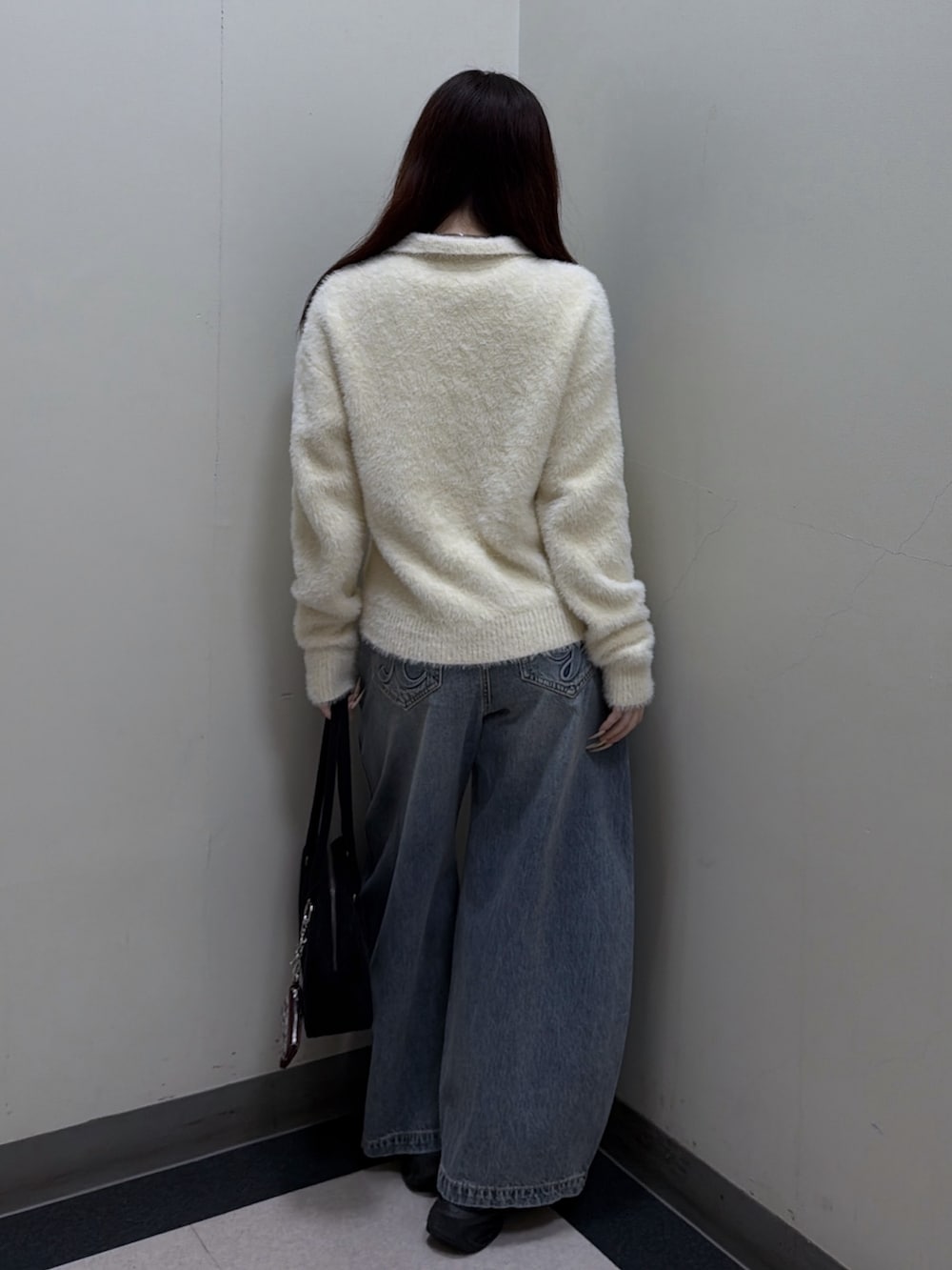 ホワイト系のニット/セーター、ブルー系のデニムパンツ、ブラック系のハンドバッグを着用したレディースの秋コーディネートの3枚目の写真