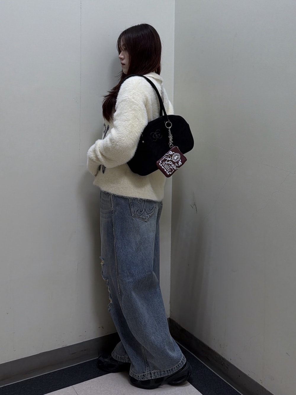 ホワイト系のニット/セーター、ブルー系のデニムパンツ、ブラック系のハンドバッグを着用したレディースの秋コーディネートの2枚目の写真