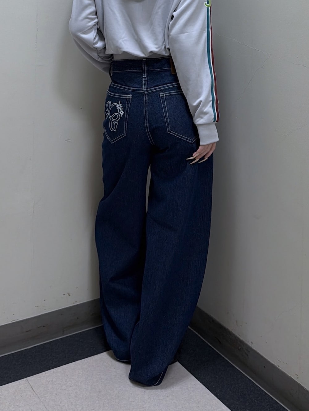 グレー系のパーカー、ブルー系のデニムパンツ、グリーン系のニットキャップ/ビーニーを着用したレディースの秋コーディネートの4枚目の写真