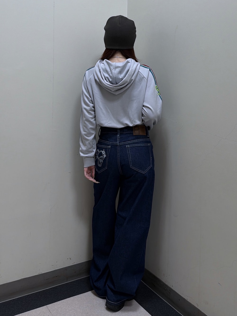 グレー系のパーカー、ブルー系のデニムパンツ、グリーン系のニットキャップ/ビーニーを着用したレディースの秋コーディネートの3枚目の写真